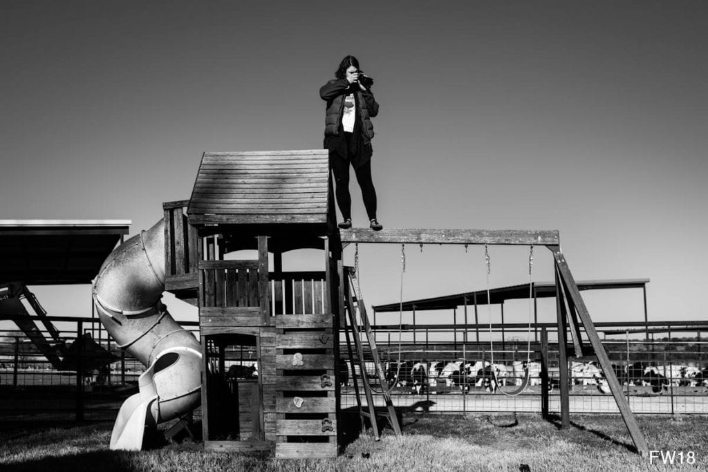 woman standing on top of swingset to take photos