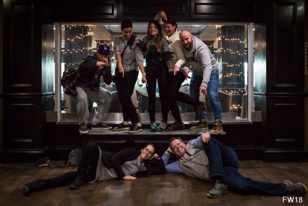 group photo in front of glass wall with people pointing at people on floor