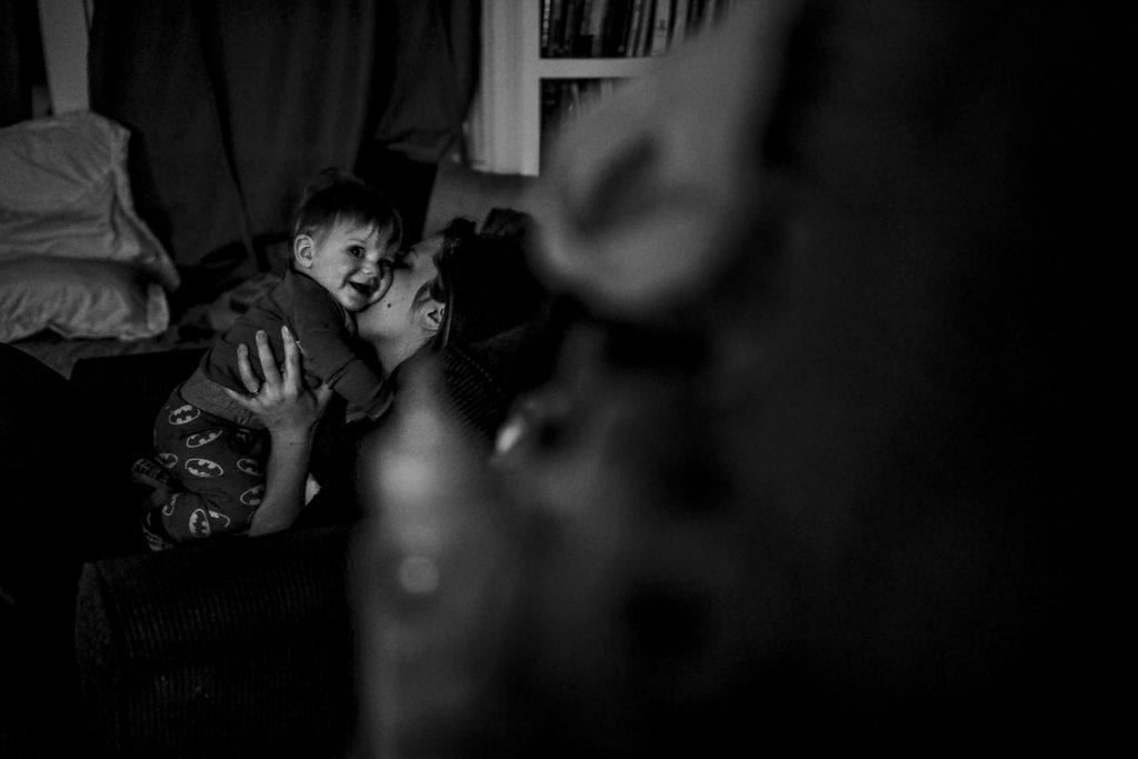 mom kisses baby in darkened room