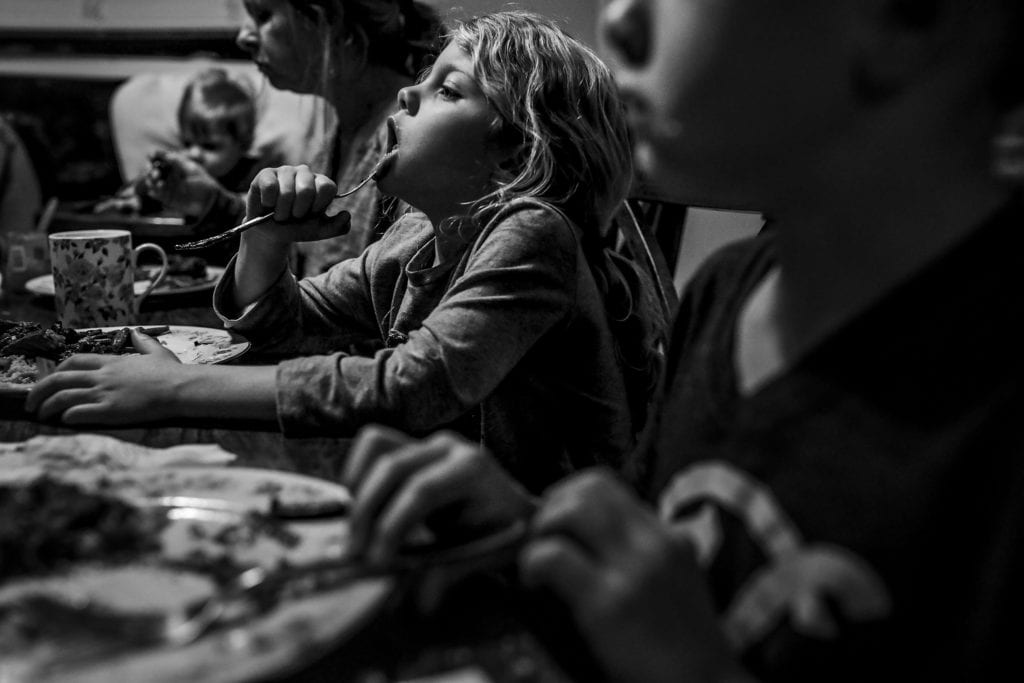 girls presses fork against lip at dinner table
