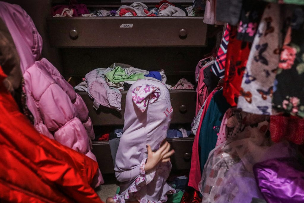 girl gets head stuck while she puts on pyjamas in cluttered closet