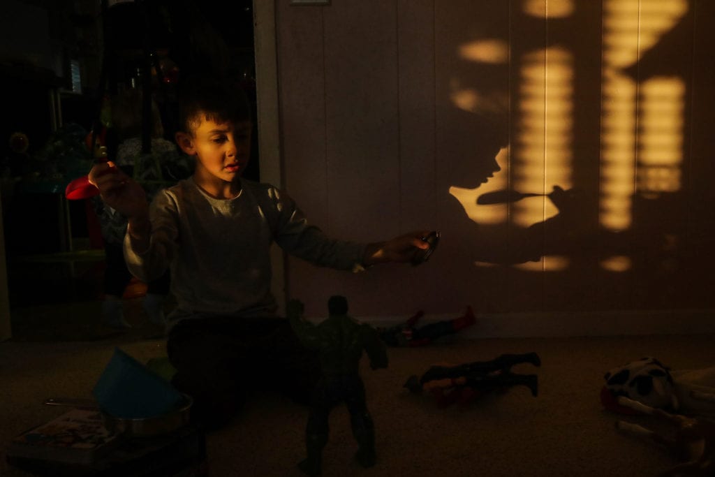 boy plays with toys while shawdow looks like he's feeding himself