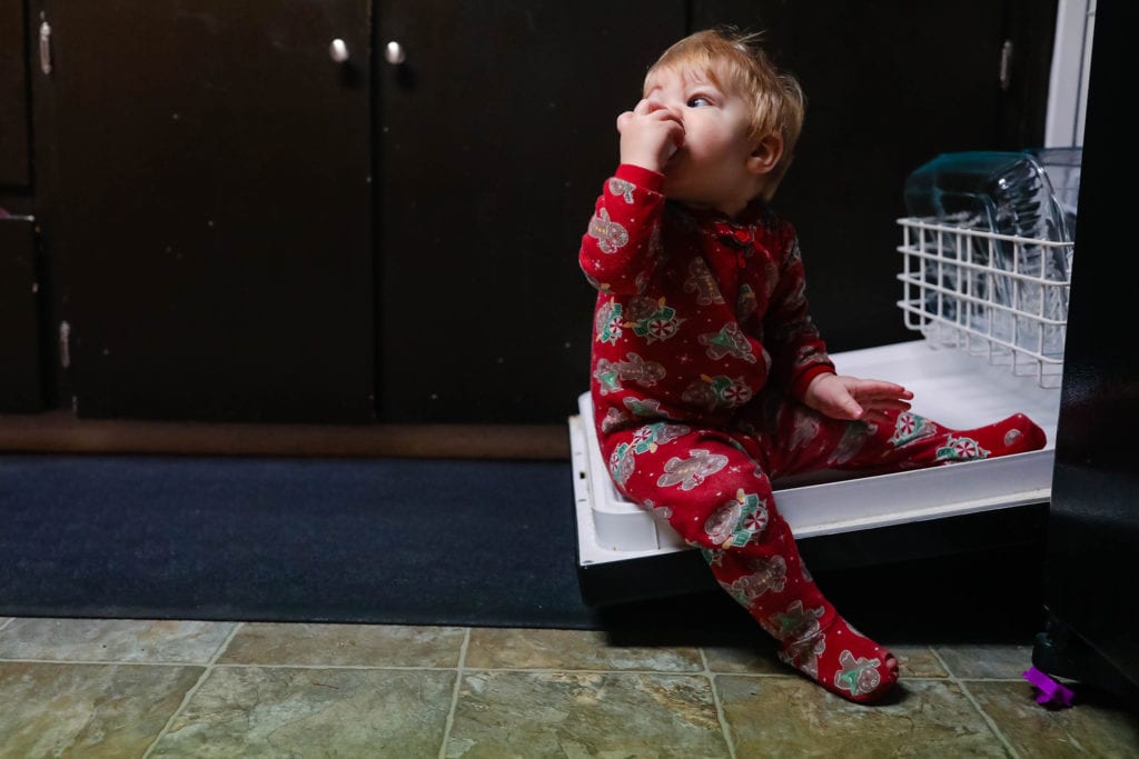 boy sits on open dishwasher door