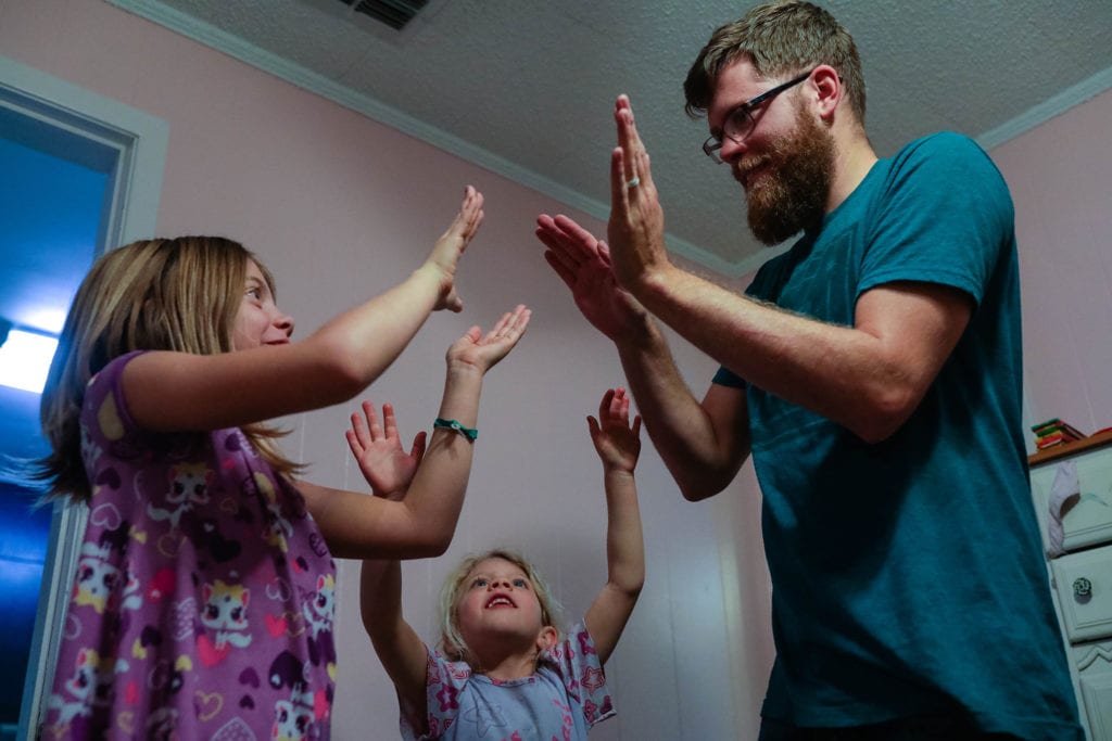 dad plays hand games with daughters