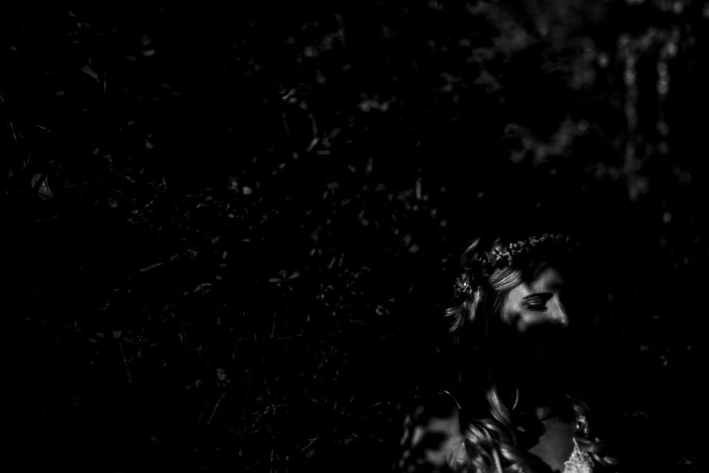 Haliburton bride stands in shadows with bright sun shining on eye