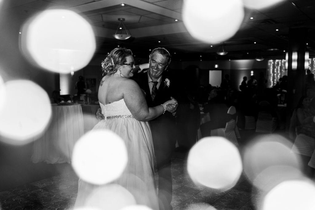 father laughs while dancing with bride