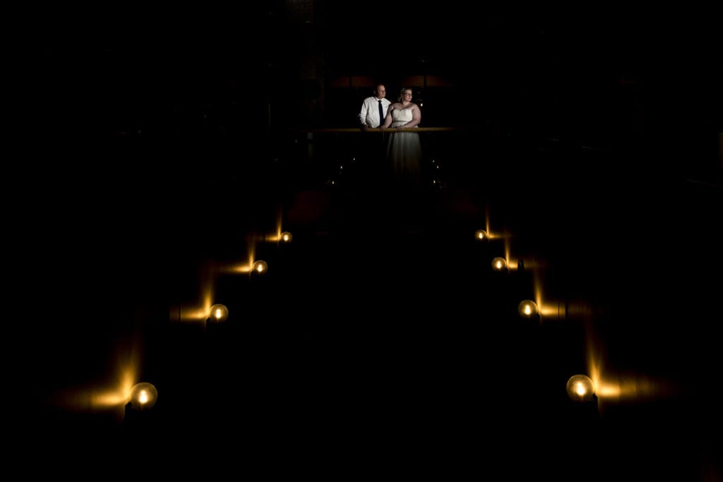 bride and groom spotlit at end of wall sconces