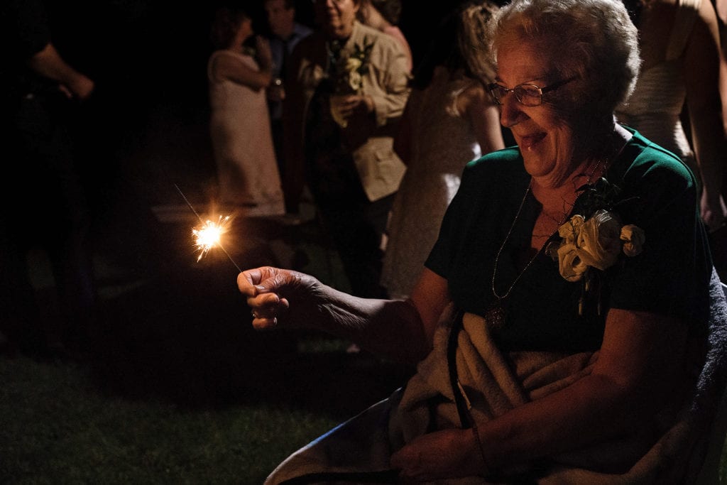 grandmother smiles widely while holding sparkler