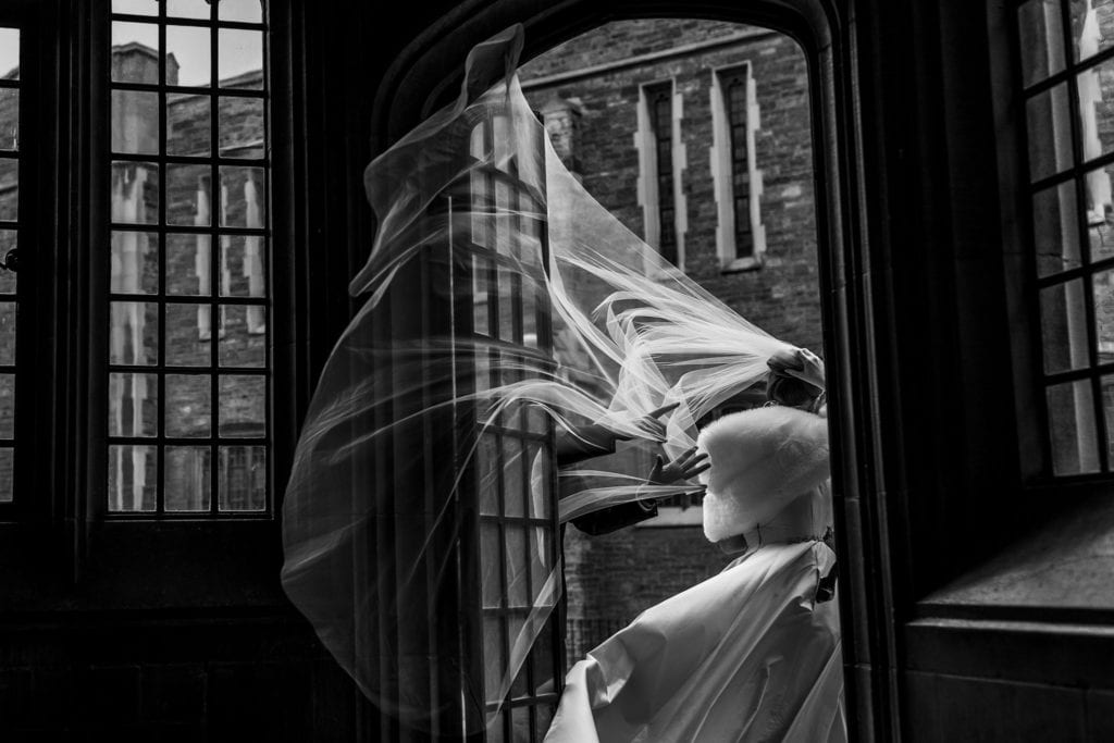 groom pushes veil out of door as wind gusts through