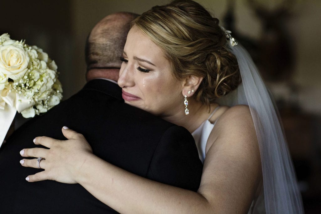 bride hugs father while crying