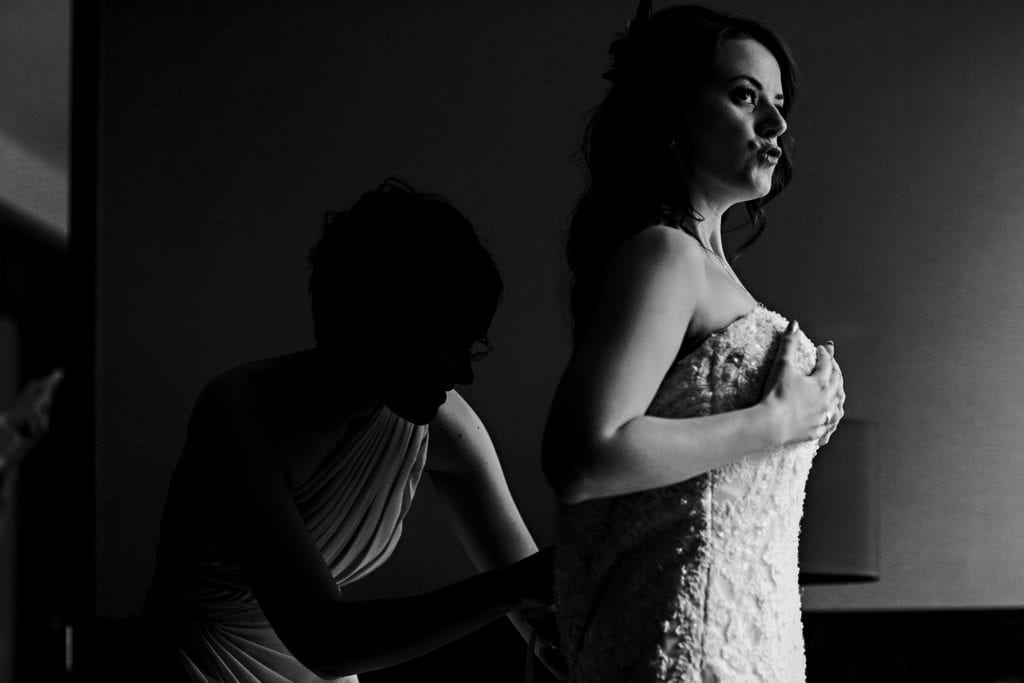 bride sucks in as dress is fastened