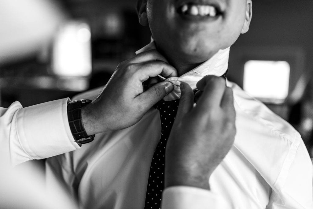 Groomsman winces as shirt button is fastened
