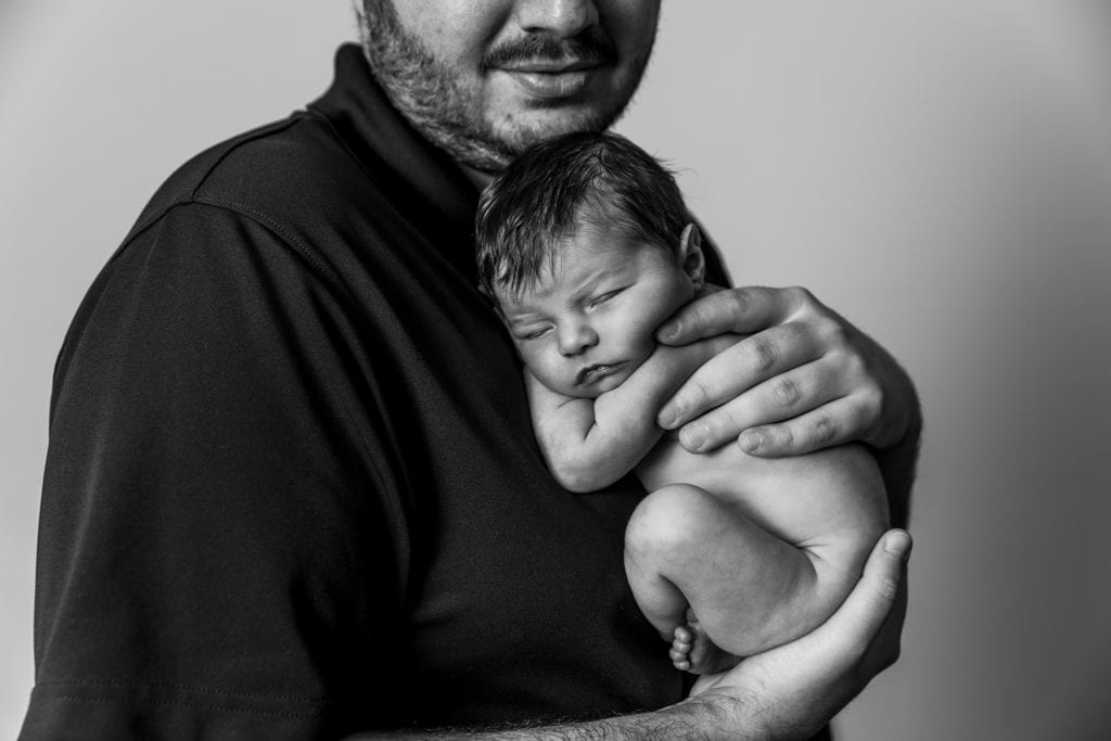 man holds baby daughter against his chest