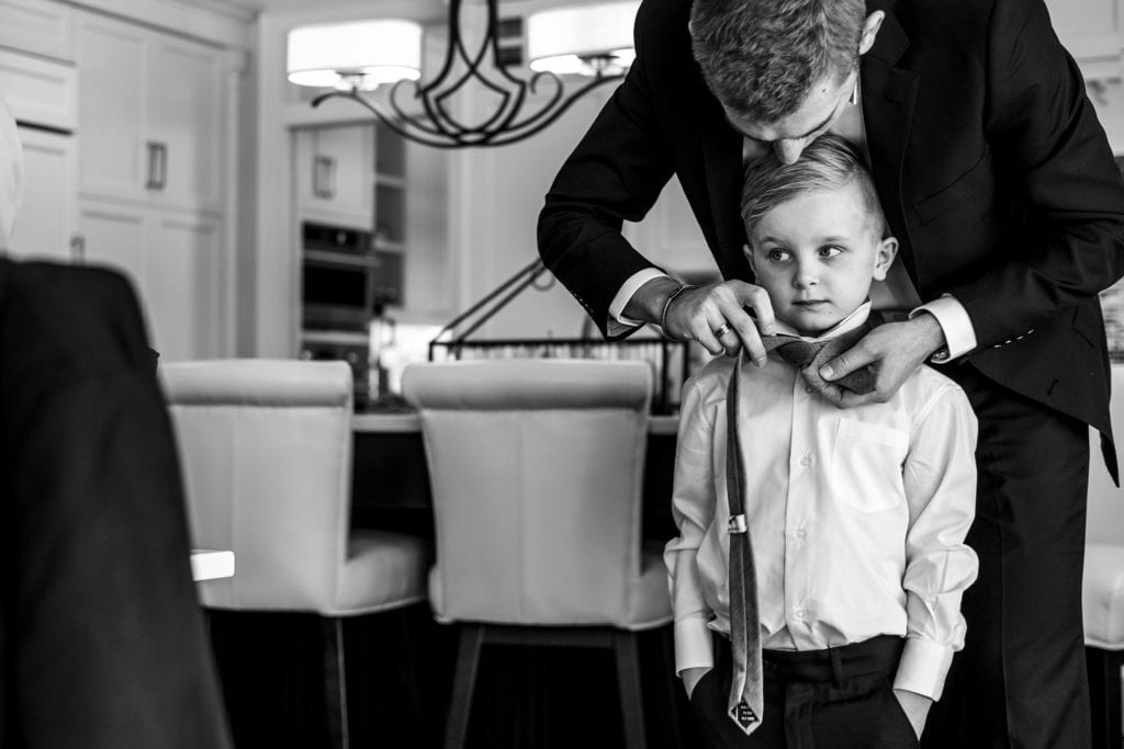 groomsman helps ring bearer tie his tie