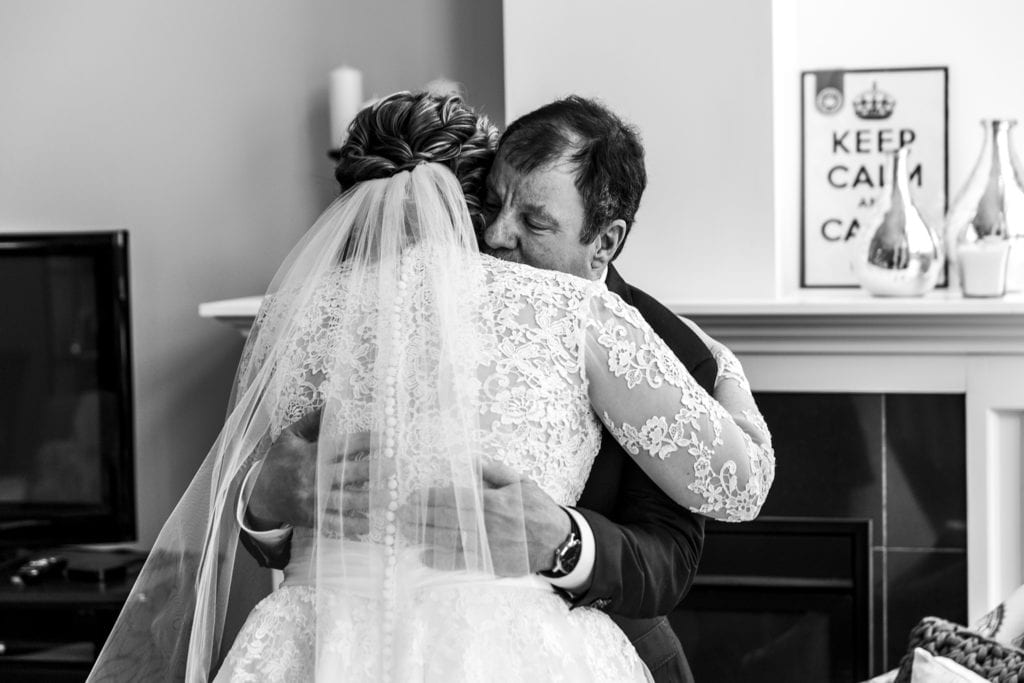 bride hugs father after getting ready for snowy Cornwall winter wedding