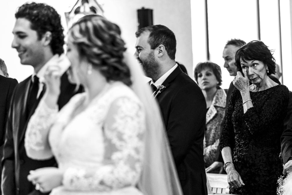bride wipes tears with tissue as mother of the groom does the same