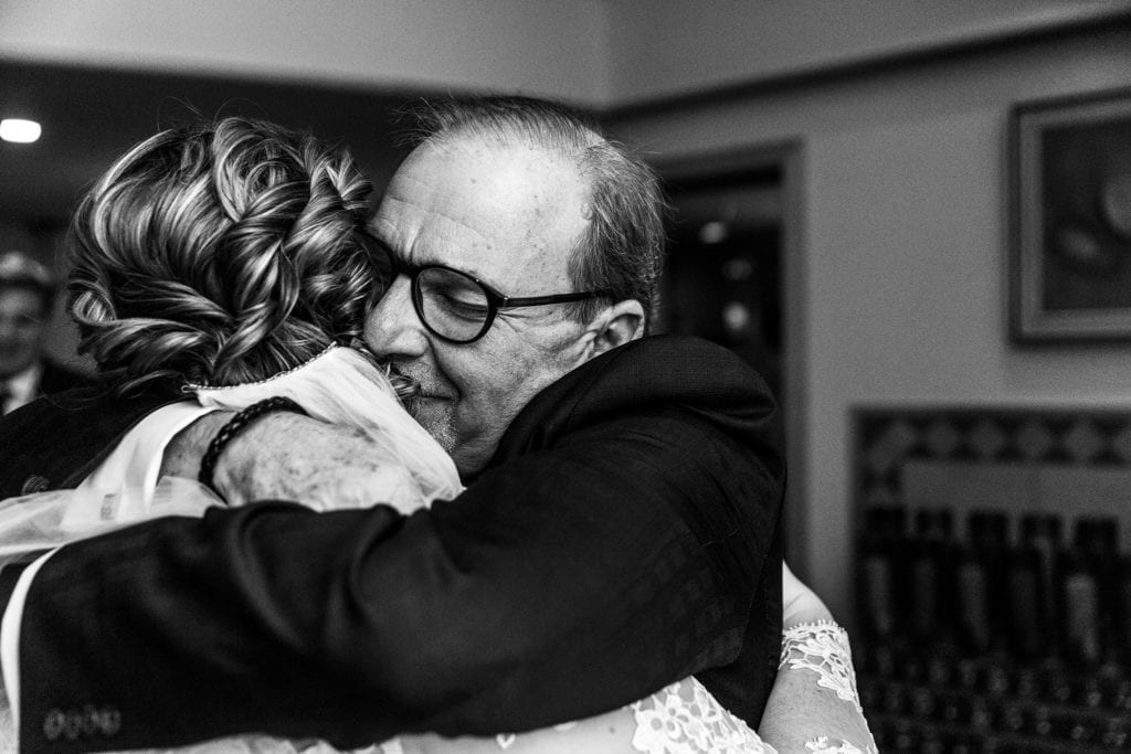 father of the groom hugs bride after Cornwall wedding ceremony