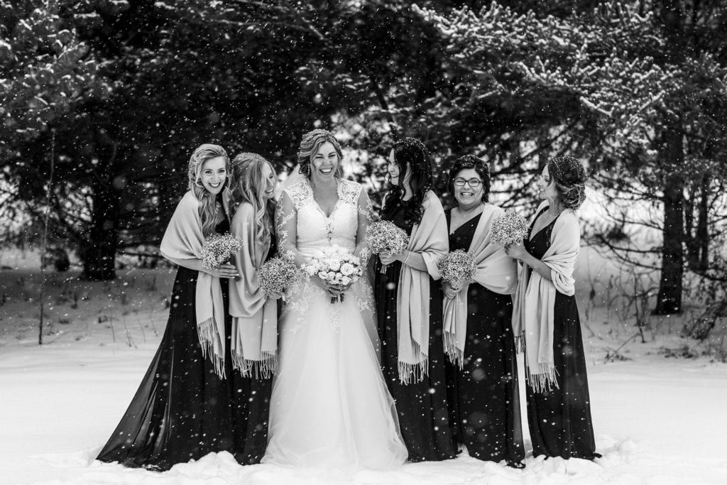 bridesmaids laugh together with bride in the snow during snowy Cornwall winter wedding