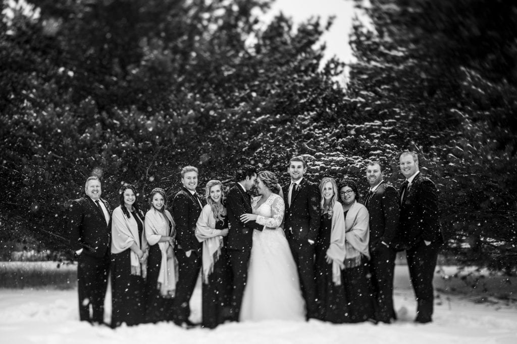 formal wedding party photo while bride and groom look at each other during snowy Cornwall winter wedding portraits
