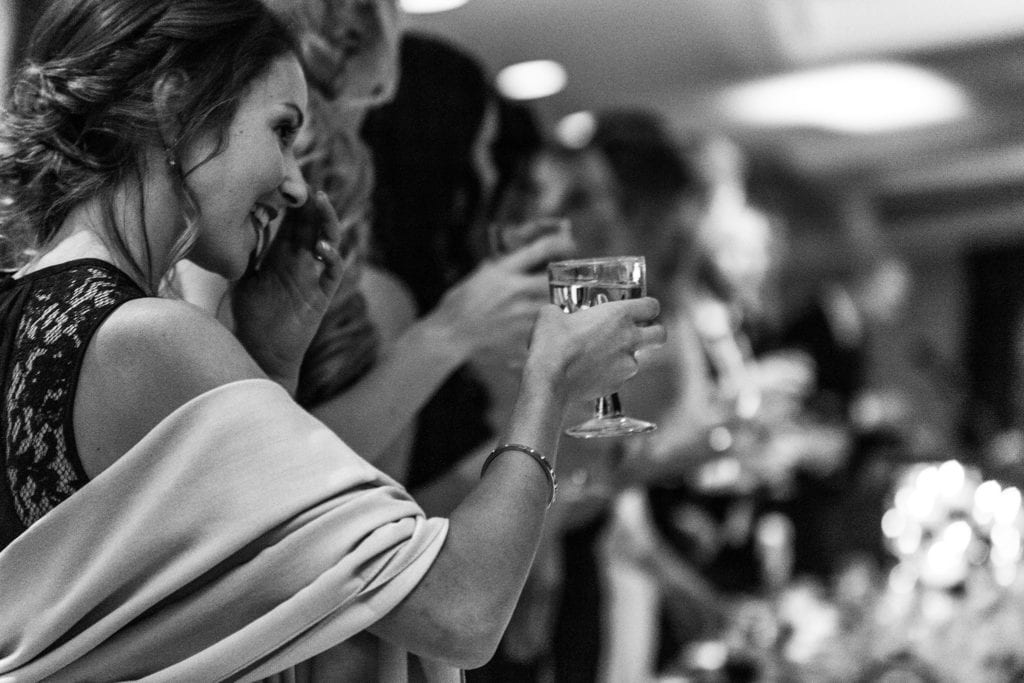 wedding party stand and raise glasses to toast bride and groom during wedding reception