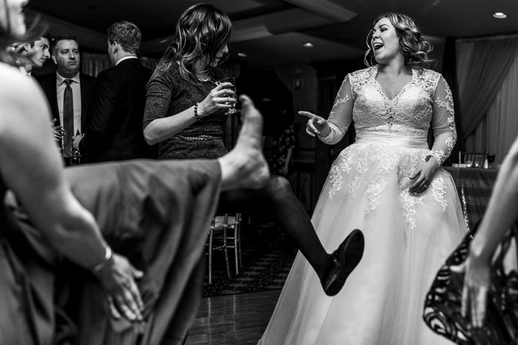 brides on dance floor with friends kicking up feet