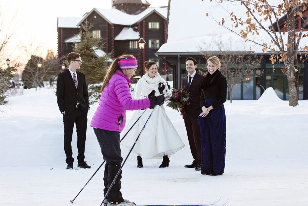 girl in pink coat skis past wedding party