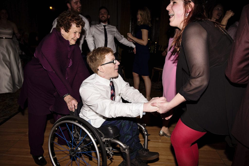 grandma and woman in red tights dance with man in wheelchair