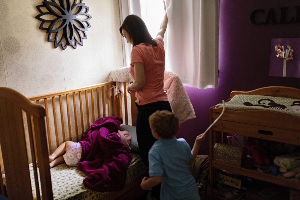 mom pulls back curtain and brother runs in with hockey stick while girl hides under blanket