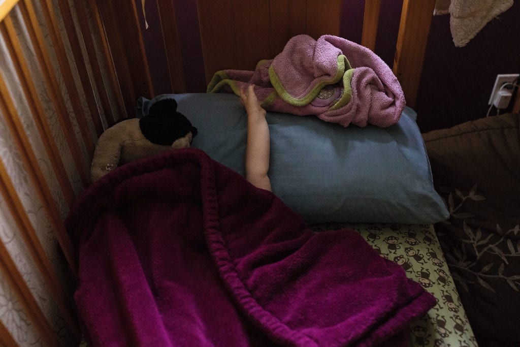 arm reaches out from under fuschia blanket to grab pink blanket