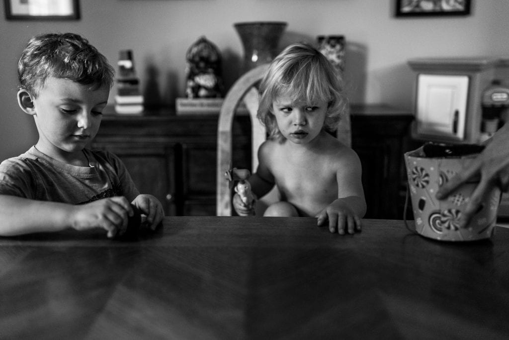 shirtless girl gives filthy look at parent removes bucket from table