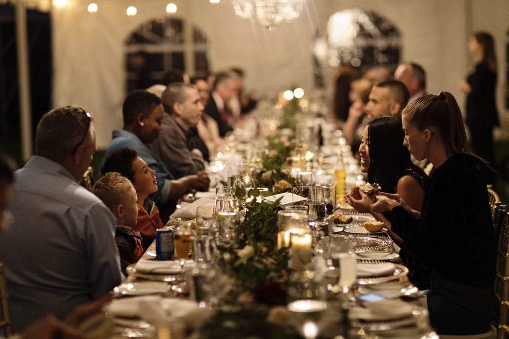 guests seated at table with greenery during dinner