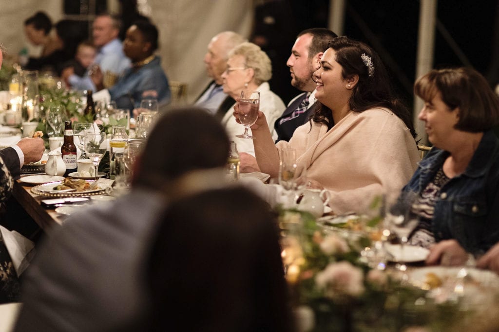 bride raises glass during backyard wedding reception