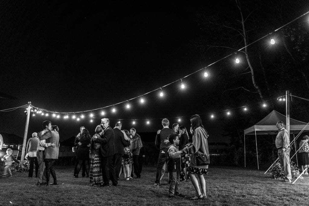 backyard wedding guests dance under string lights