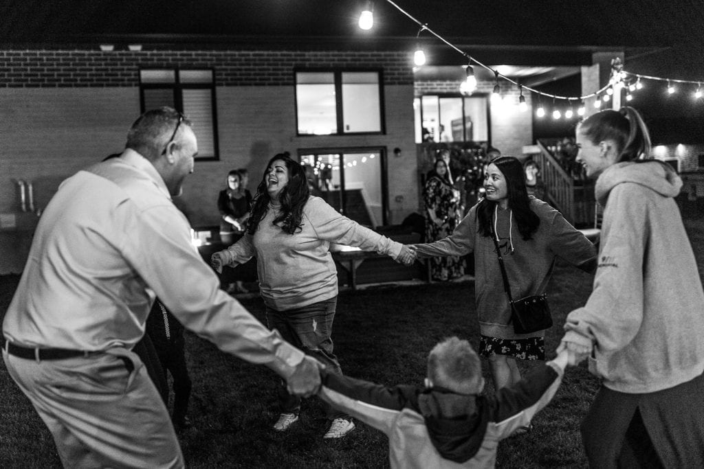 backyard wedding guests dance in circle holding hands