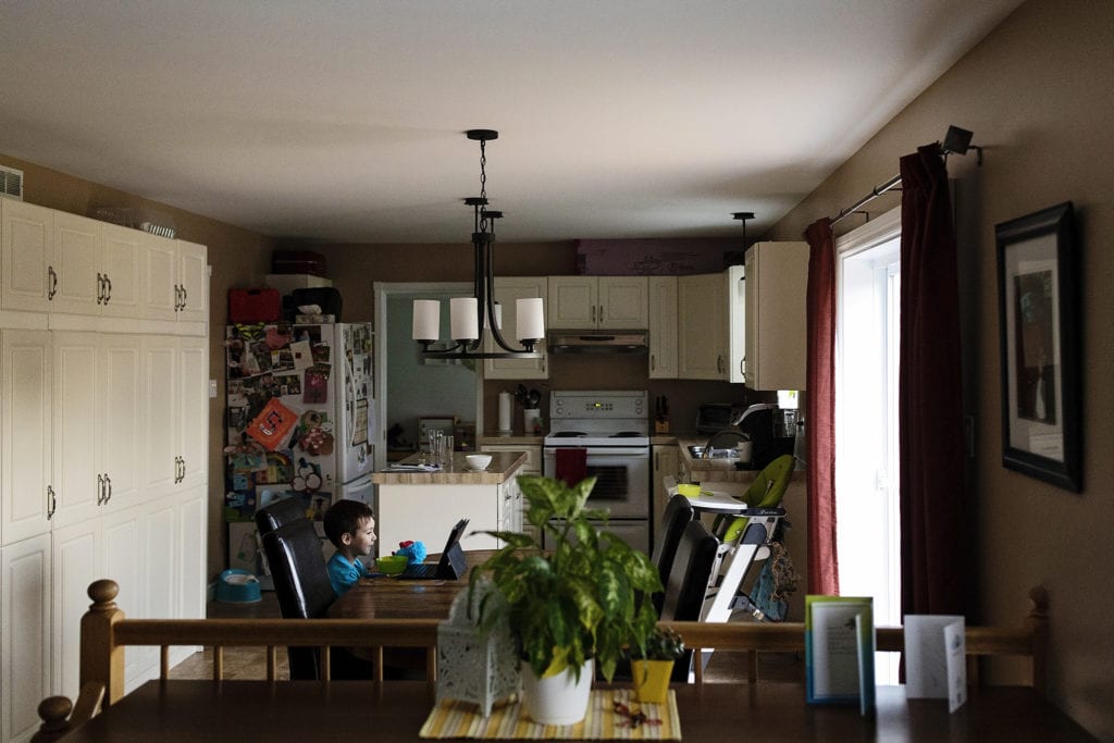 boy sits at kitchen table alone with ipad and cereal