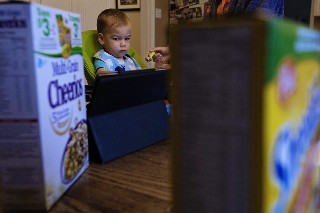 toddler scowls as spoon with cereal is reached towards mouth by parent