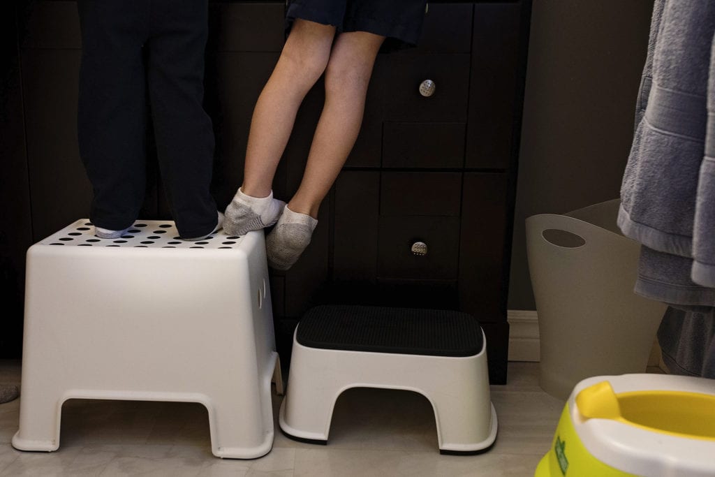 boy leans sideways off stepstool