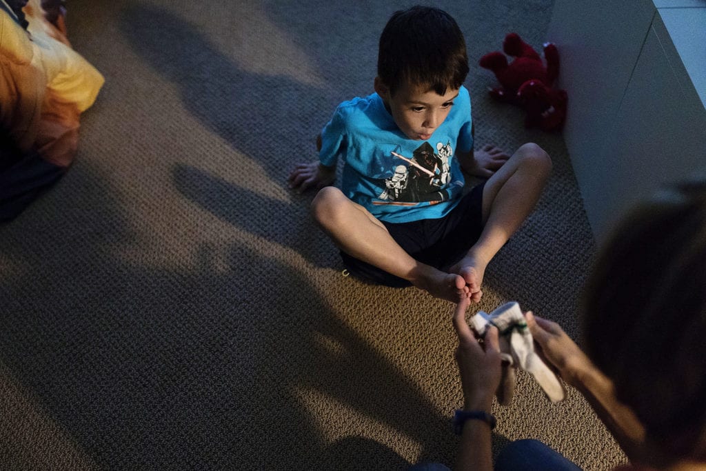 boy in blue shirt gets help from mom with socks
