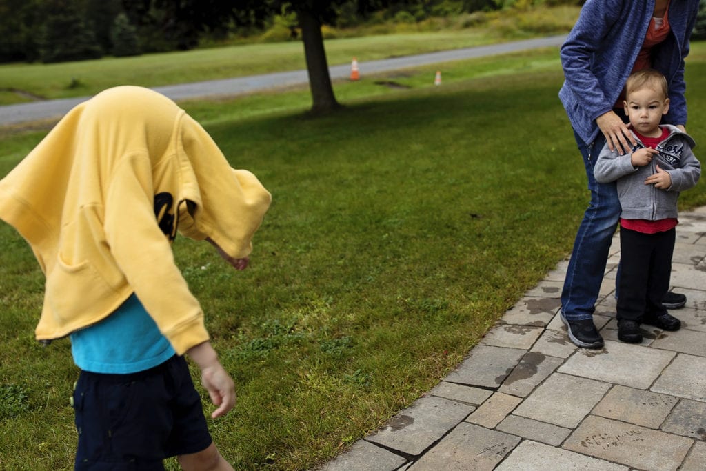 toddler looks at boy with yellow sweatshirt over head
