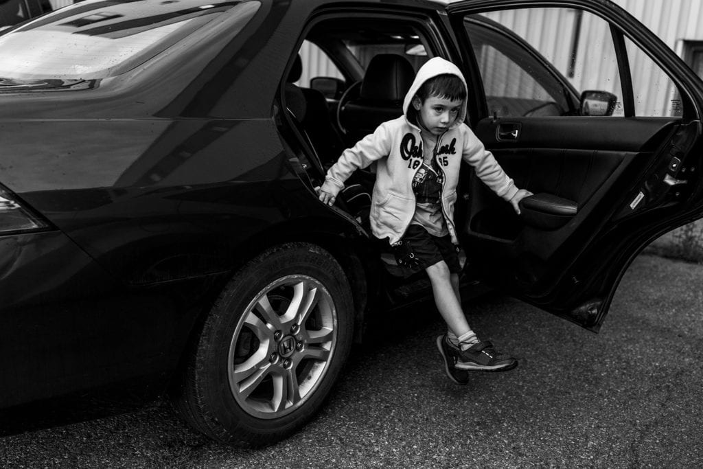 boy swings legs while getting out of car