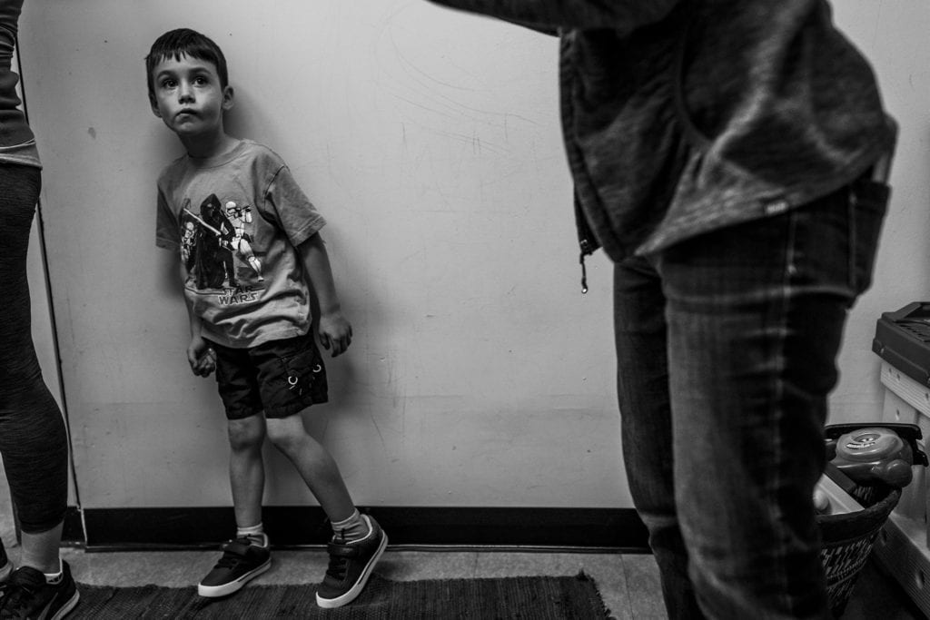 boy stands against wall looking uncertain