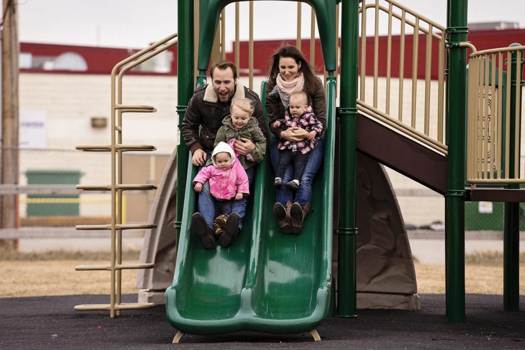 mom and dad go down slide with three kids
