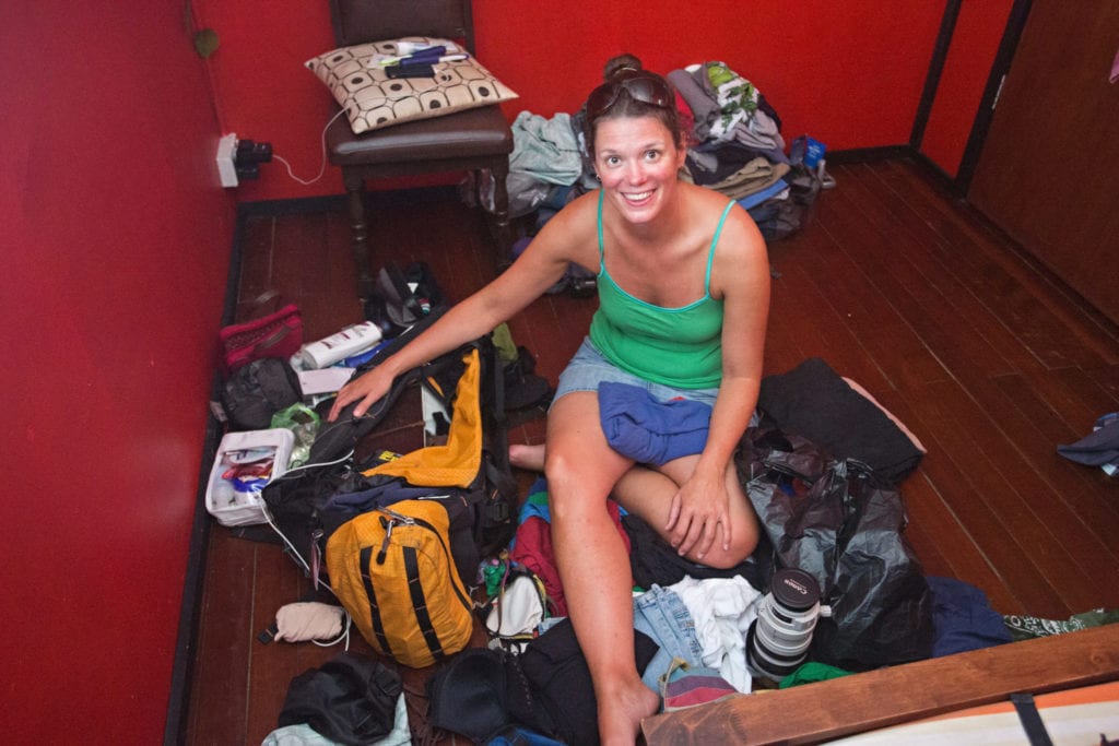 woman in green tank top sitting next to unpacked backpack