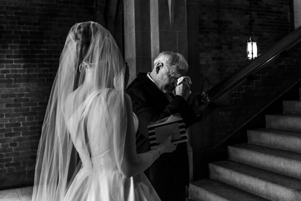 bride stands with father as he wipes tears