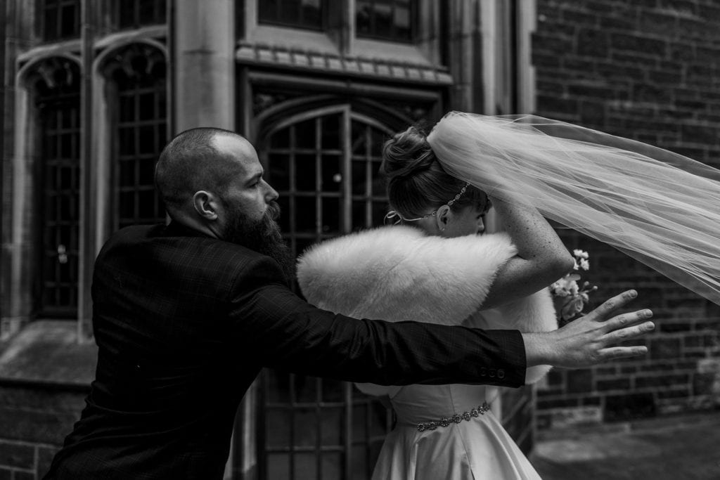 bride holds veil as groom releases it and it blows out of reach