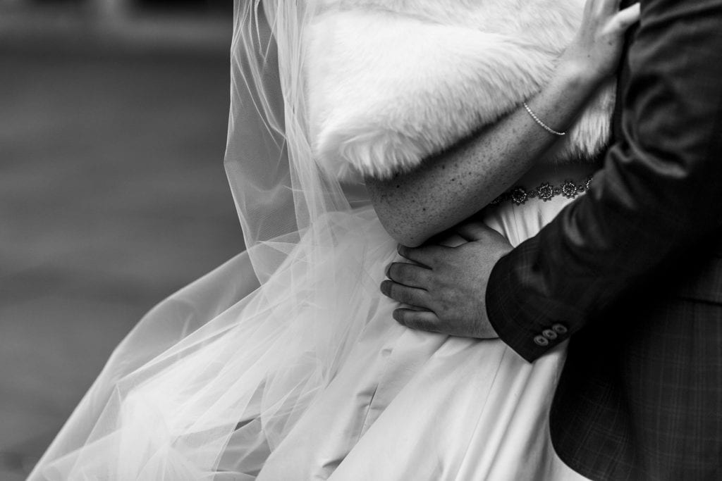 groom holds bride's waist as she places hand on his chest