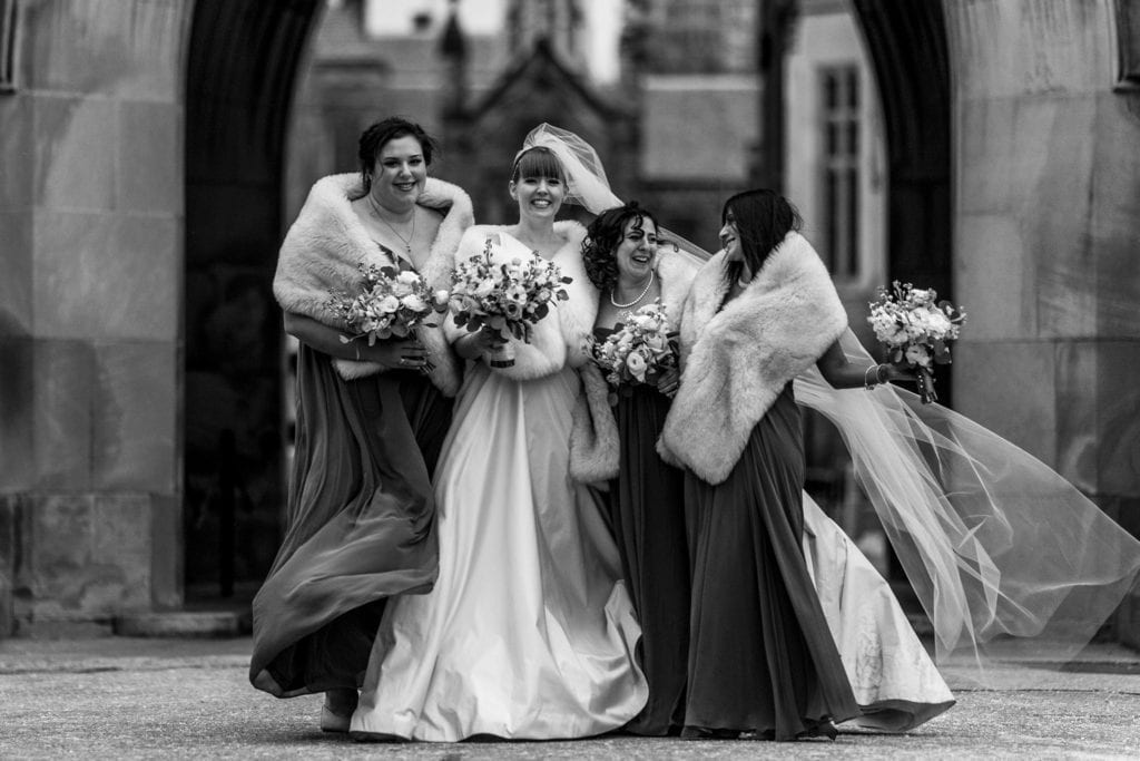 bride laughs with bridesmaids in fur stoles