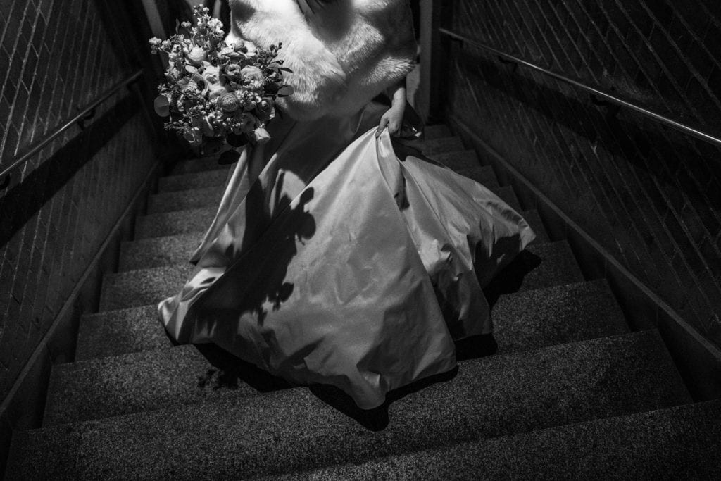 bride lifts dress as she walks up stairs