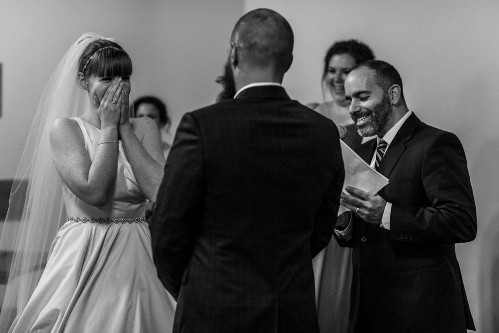 bride covers mouth with surprise during wedding ceremony