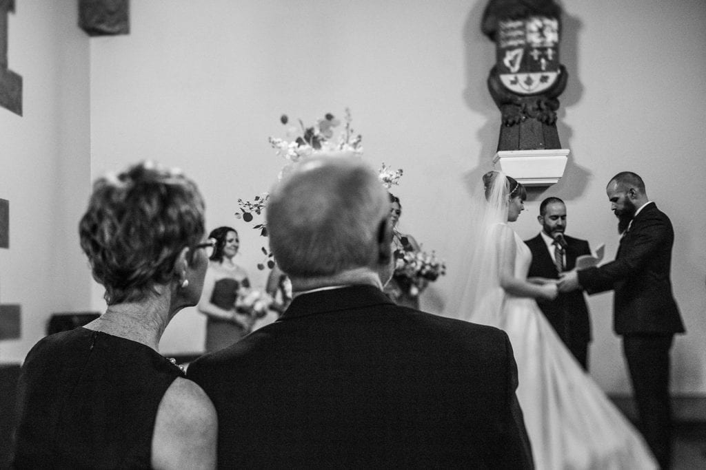 bride and groom exchange vows while parents watch on 